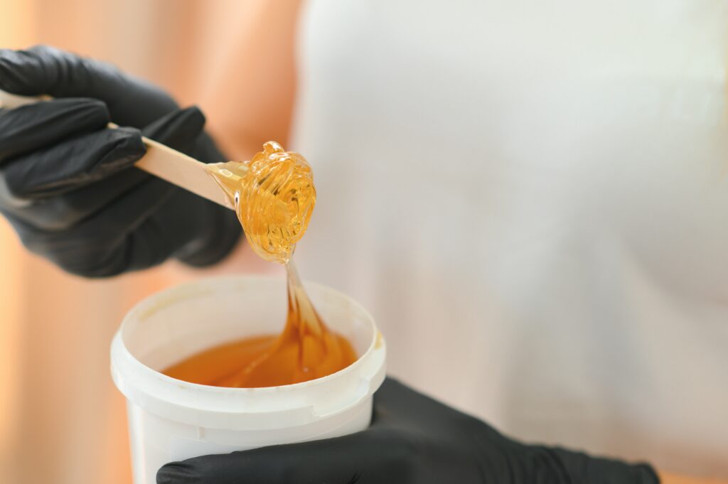 Portrait of a female beautician holding a jar of sugar paste for sugaring.